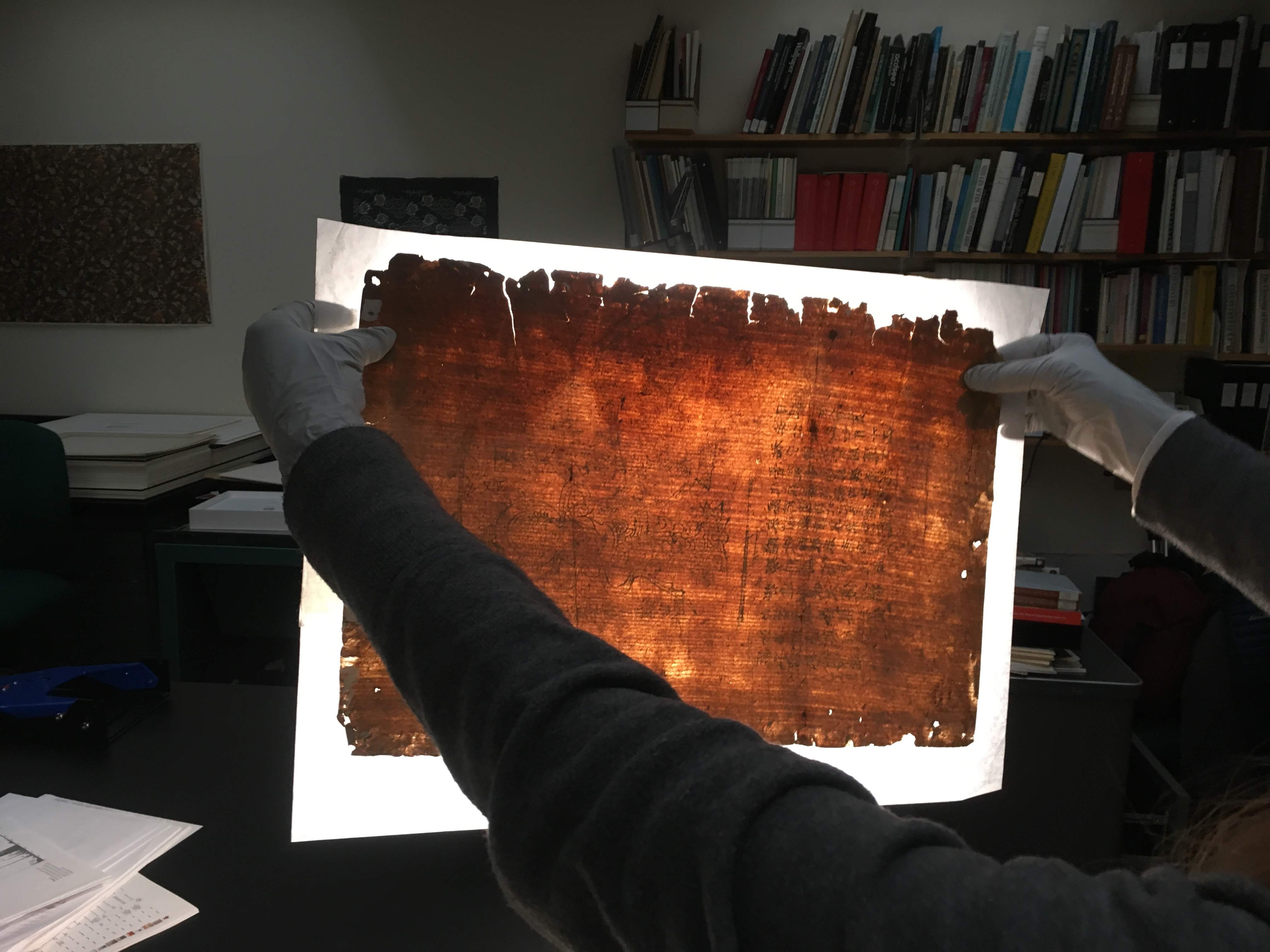 Holding a manuscript leaf up to the light